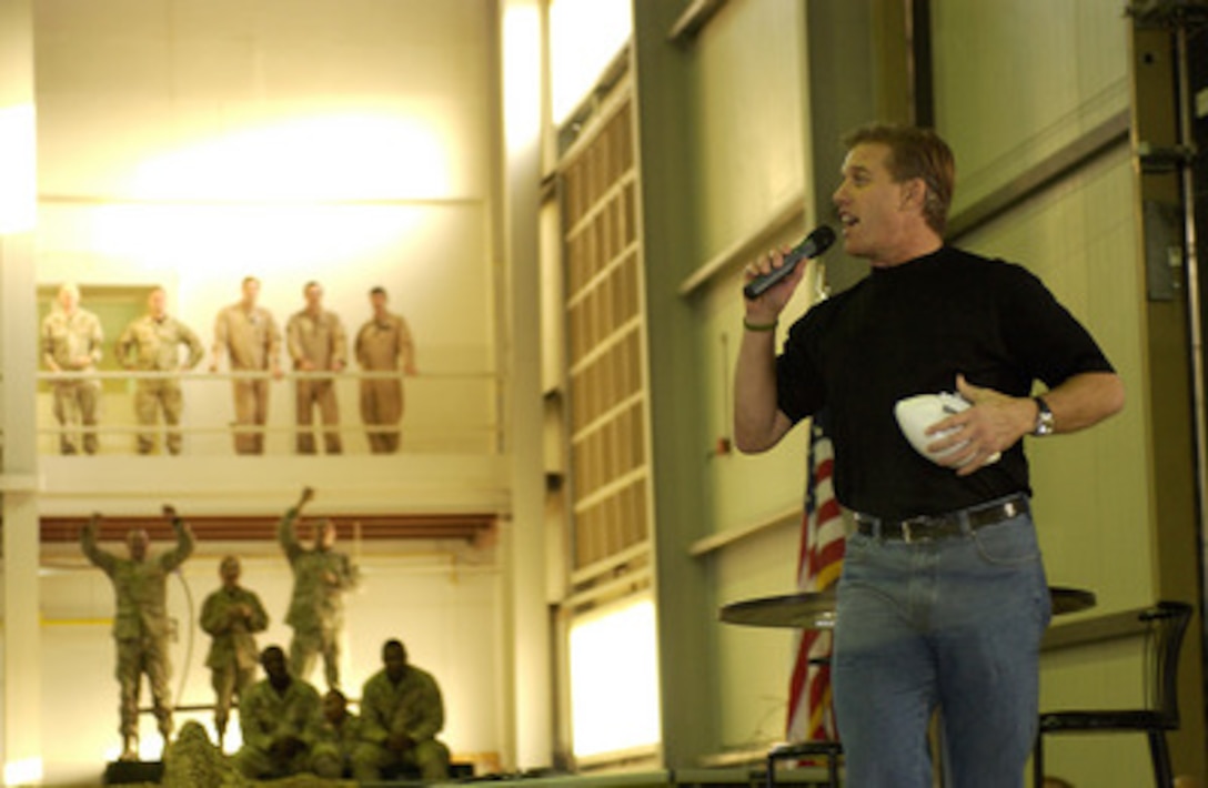 Hall of Fame Quarterback John Elway talks to the troops as he gets ready to fire a few footballs to the crowd at Ali al Salem Air Base, Kuwait, during a United Services Organization tour on Dec. 13, 2004. Elway joined Chairman of the Joint Chiefs of Staff Gen. Richard B. Myers, U.S. Air Force, and Blake Clarke, Leann Tweedon and Robin Williams on the USO tour to meet, entertain and thank the deployed troops. 