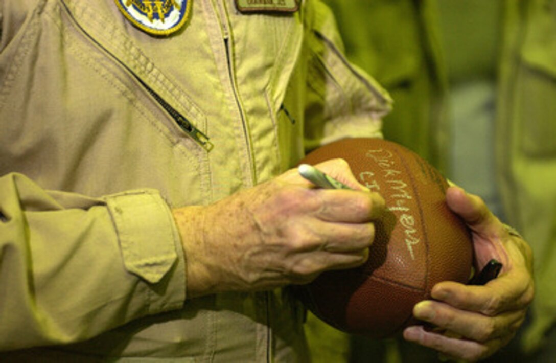 Chairman of the Joint Chiefs of Staff Gen. Richard B. Myers, U.S. Air Force, autographs a football at Camp Virginia, Kuwait, during a United Services Organization tour on Dec. 13, 2004. Myers, Blake Clarke, John Elway, Leann Tweedon and Robin Williams are on a USO tour to meet, entertain and thank the deployed troops. 