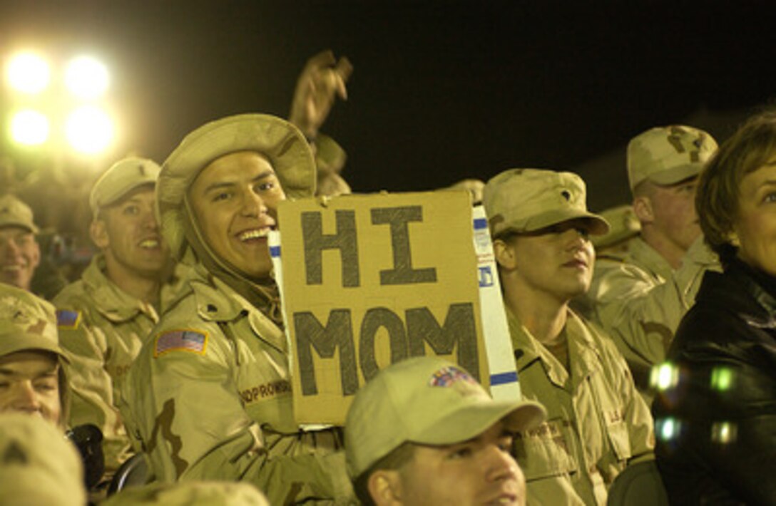 A U.S. soldier is ready for the cameras as he holds his cardboard "Hi Mom" sign at Camp Virginia, Kuwait, on Dec. 13, 2004. The soldier is part of the audience at a United Services Organization tour hosted by Chairman of the Joint Chiefs of Staff Gen. Richard B. Myers, U.S. Air Force. Myers, Blake Clarke, John Elway, Leann Tweedon and Robin Williams are on the USO tour to meet, entertain and thank the deployed troops. 