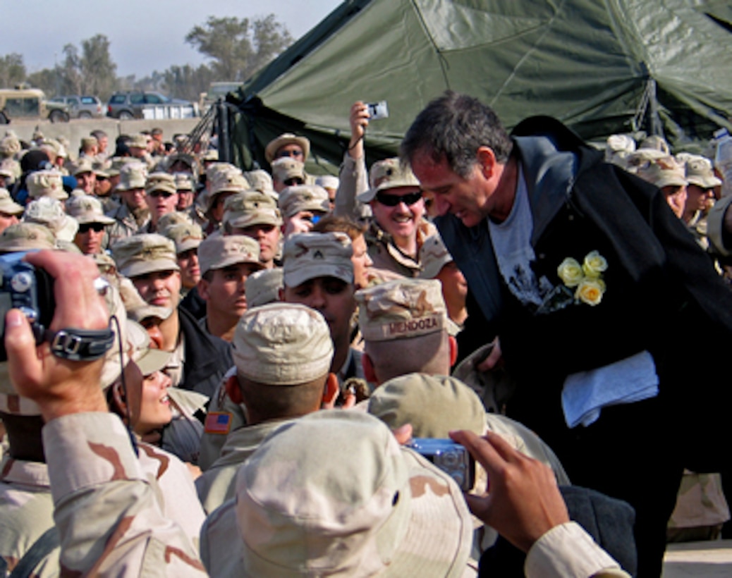 Robin Williams shakes hands and poses for photos with some of the troops gathered at the Camp Liberty Post Exchange in Baghdad, Iraq, during a United Services Organization tour on Dec. 14, 2004. Williams joined Chairman of the Joint Chiefs of Staff Gen. Richard B. Myers, U.S. Air Force, Blake Clarke, John Elway and Leann Tweedon on the USO tour to meet, entertain and thank the deployed troops. 