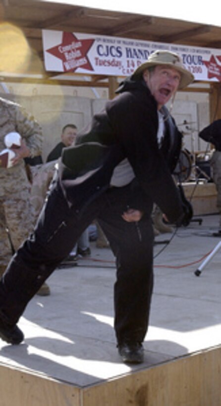 Robin Williams mugs for the audience as he tosses a football out into the crowd of troops gathered at the Camp Liberty Post Exchange in Baghdad, Iraq, during a United Services Organization tour on Dec. 14, 2004. Williams joined Chairman of the Joint Chiefs of Staff Gen. Richard B. Myers, U.S. Air Force, Blake Clarke, John Elway and Leann Tweedon on the USO tour to meet, entertain and thank the deployed troops. 