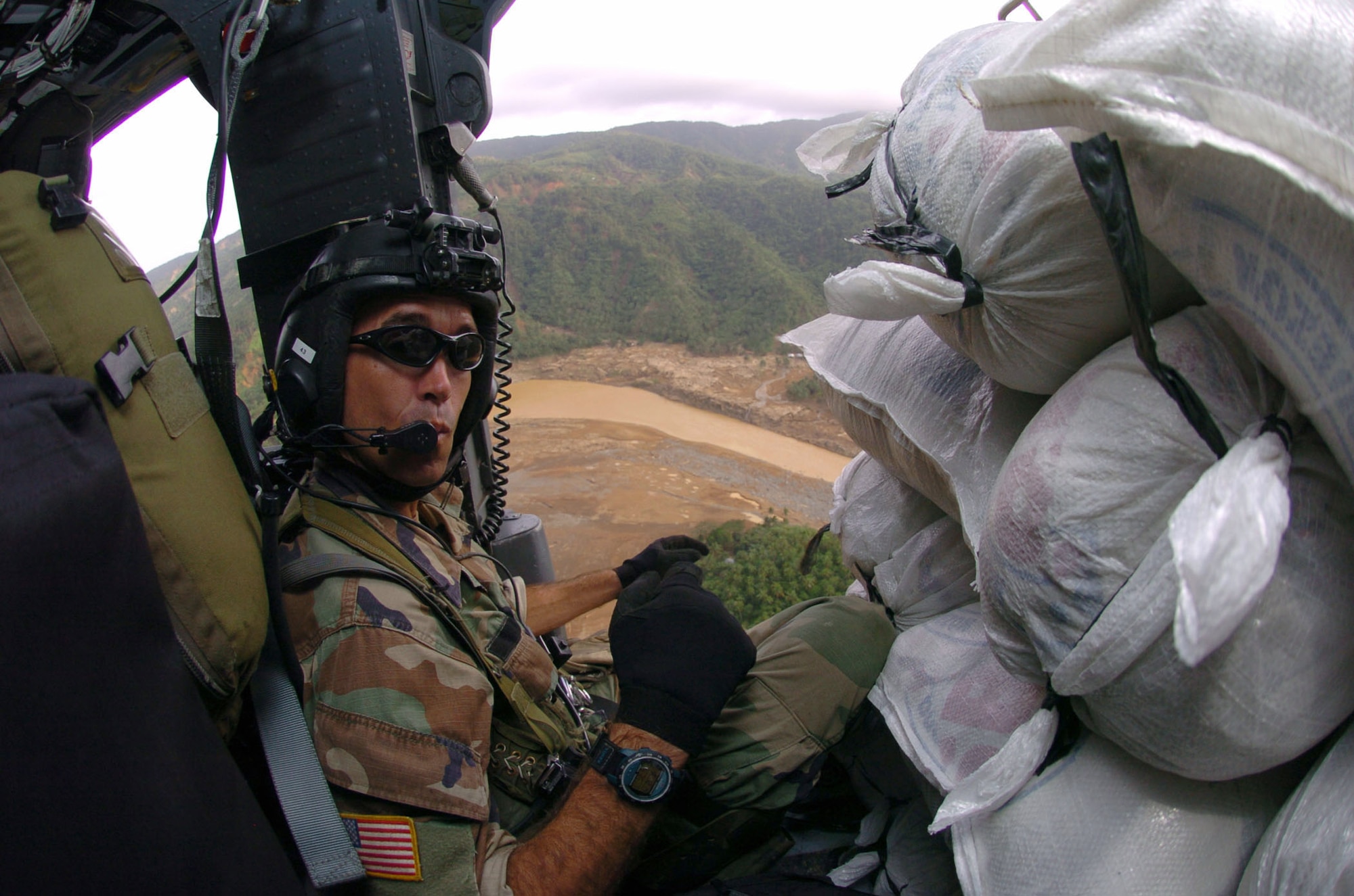 OVER QUEZON PROVINCE, Philippines -- Tech. Sgt. Don Currier delivers sacks of supplies aboard an HH-60 Pave Hawk helicopter to Real City, Philippines, during typhoon relief operations. About 600 U.S. servicemembers are providing humanitarian assistance and disaster relief to residents of Quezon Province where widespread flooding displaced about 168,000 people and left more than 1,400 dead or missing.  Air Force and Marine helicopters are flying daily missions to the stricken areas. Sergeant Currier is a pararescueman from the 33rd Rescue Squadron at Kadena Air Base, Japan. (U.S. Air Force photo by Master Sgt. Val Gempis)