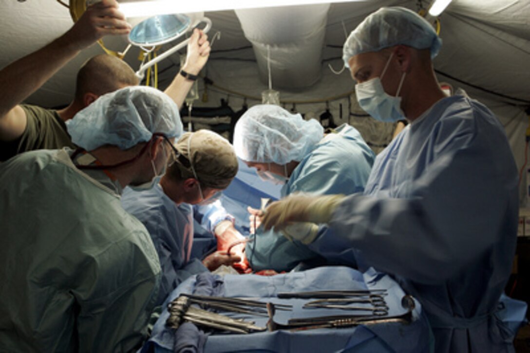 U.S. Navy surgeons and hospital corpsman assigned to the Surgical/Shock Trauma Platoon at Camp Taqaddum in Iraq operate on a Marine injured by an improvised explosive device on Nov. 17, 2004. The shock trauma platoon is part of the 1st Force Service Support Group and one of three major immediate surgical and trauma care teams assigned to Marine forces operating in Iraq. 