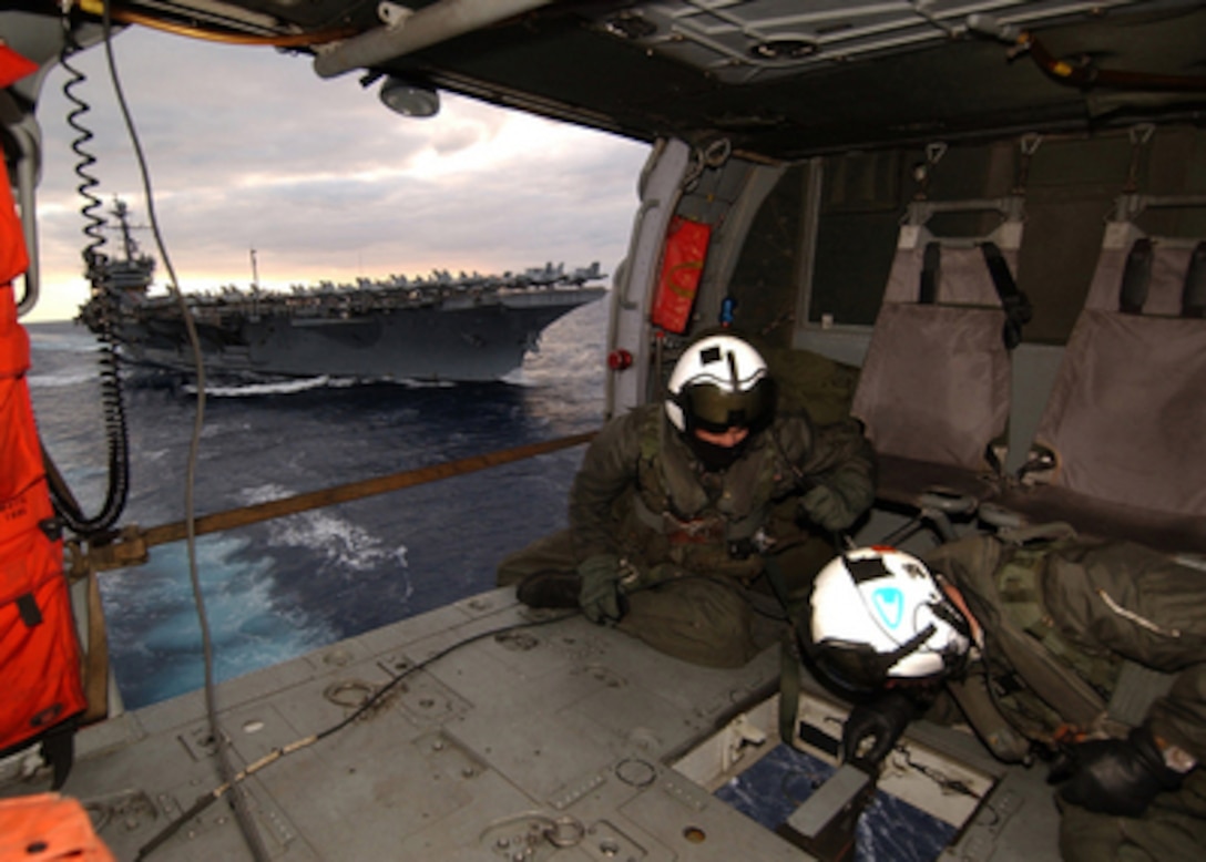 Navy aircrewmen Petty Officer 2nd class Joseph Broderick and Petty Officer 3rd class Christopher Lovell keep a watchful eye below as a cargo pallet is attached to the hook of their MH-60S Knighthawk helicopter during a vertical replenishment operation in the Atlantic Ocean on Dec. 6, 2004. The Knighthawk is deployed aboard the USS Seattle (AOE 3) from Helicopter Combat Support Squadron 8. The Seattle is a fast combat support ship that provides logistical support to the USS John F. Kennedy (CV 67) Carrier Strike Group. Broderick is a Navy aviation machinist's mate and Lovell an aviation electrician's mate. 