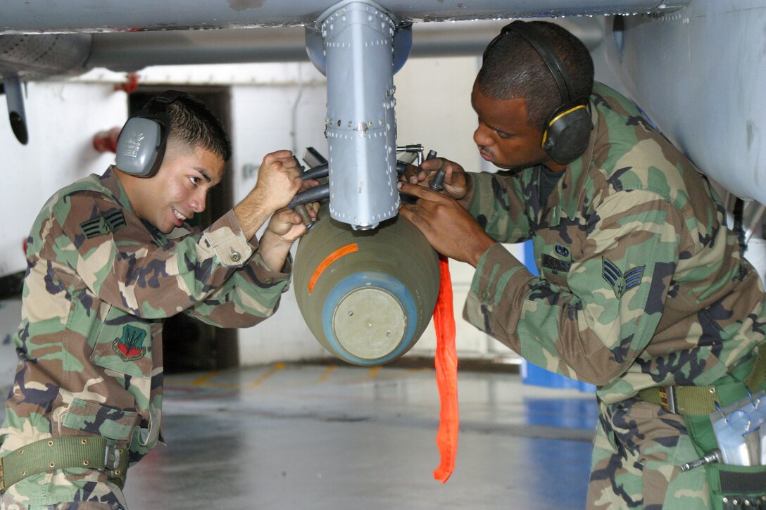 POPE AIR FORCE BASE, N.C. -- Senior Airmen Oscar Mejia and Doug Parker load a MK-82 high-drag 500-pound bomb onto an A-10 Thunderbolt II during a load crew competition here Dec. 10.  The Airmen are assigned to the 23rd Aircraft Maintenance Squadron.  (U.S. Air Force photo by Lisa Terry McKeown)