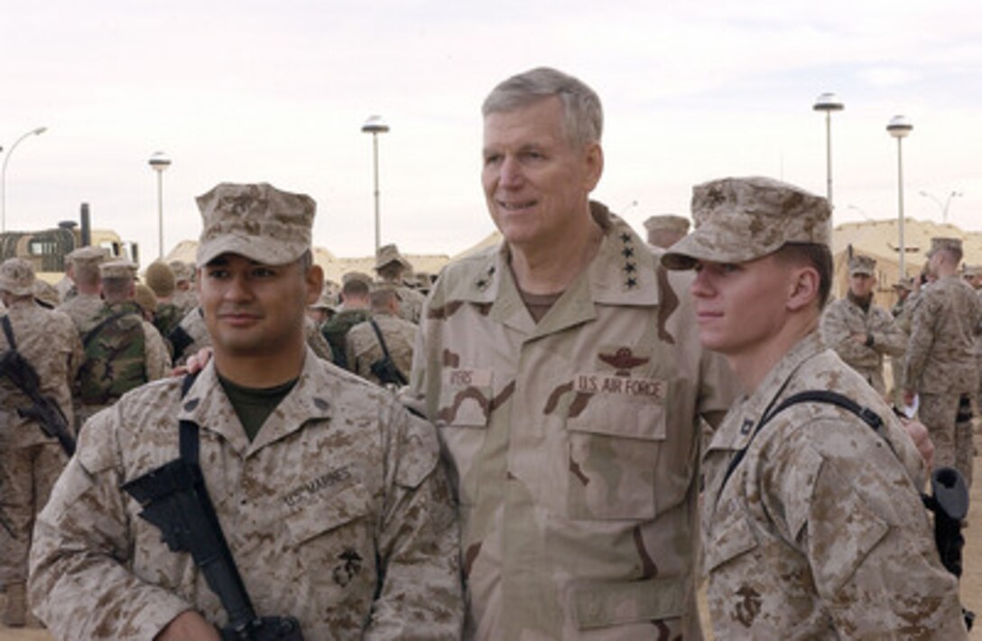 Chairman of the Joint Chiefs of Staff Gen. Richard B. Myers (center), U.S. Air Force, poses for photographs with two U.S. Marines deployed to Al Asad, Iraq, during a United Services Organization show on Dec. 14, 2004. Myers, Blake Clark, John Elway, Leann Tweeden and Robin Williams are on a USO tour to meet, entertain and thank the deployed troops. 