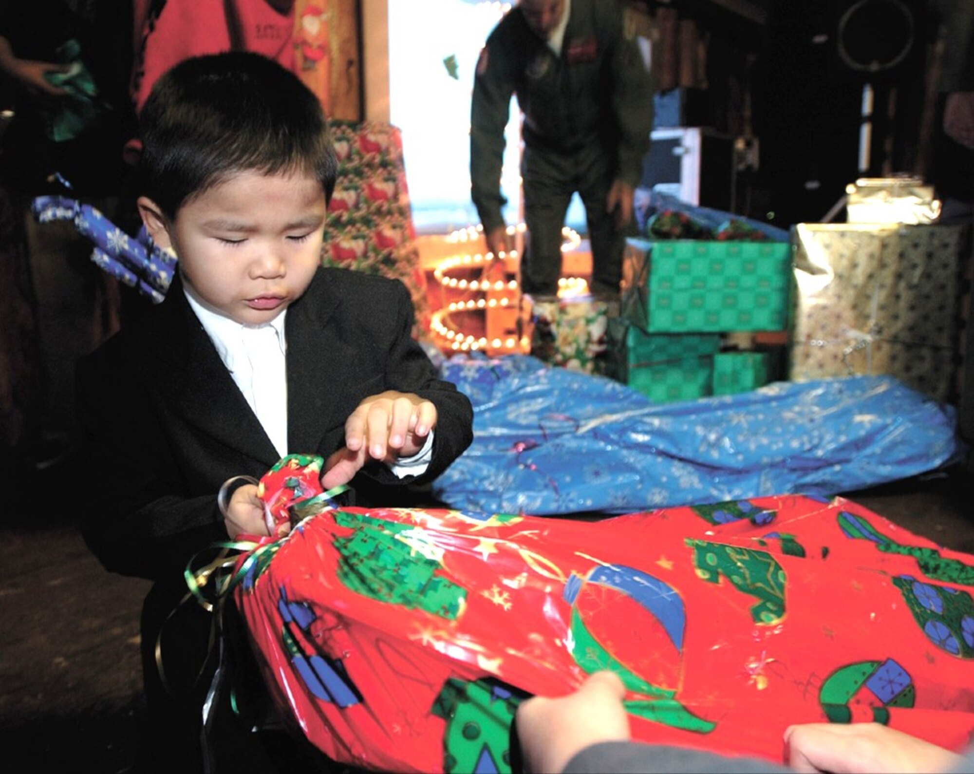 ARCTIC VILLAGE, Alaska -- Kobe Nickolai unwraps a present from Santa Claus.  Santa traveled here on a C-130 Hercules from Elmendorf Air Force Base's 517th Airlift Squadron to deliver gifts and supplies for the 37th year in a row.  (U.S. Air Force photo by Tech. Sgt. Keith Brown)