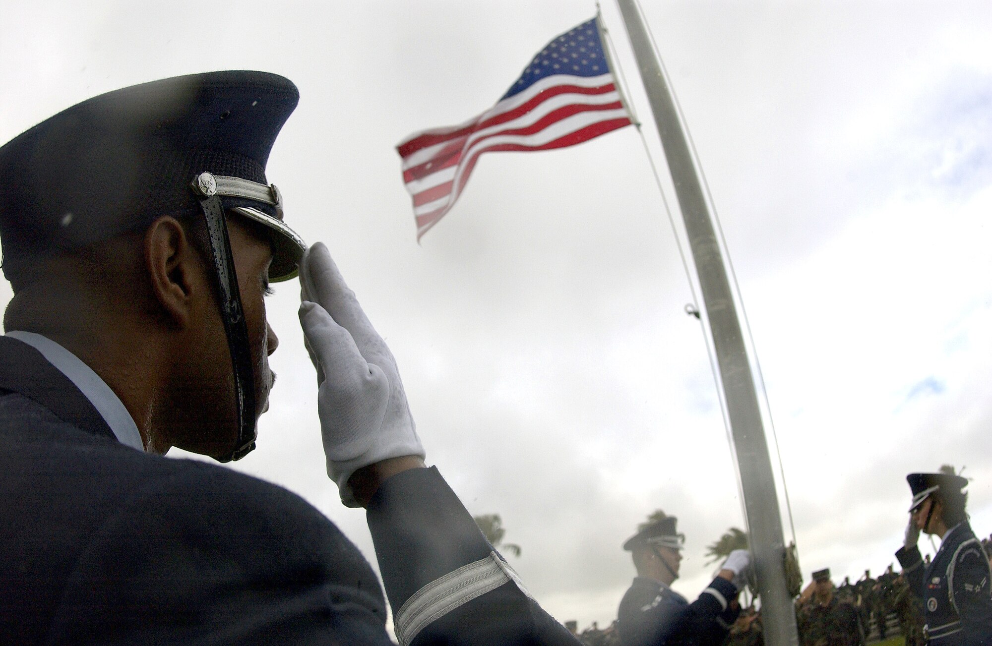 ANDERSEN AIR FORCE BASE, Guam -- Staff Sgt. John Christian (foreground) salutes as Airmen 1st Class Curtis Latham (left) and Kristin Ruleau, members of the base Blue Knights Honor Guard, lower the flag to half-mast in honor of fallen Airmen during a ceremony here Dec. 17 to mark the 32nd anniversary of Arch Light.  The base's Arc Light Memorial Park is a tribute to the 33 Airmen from Andersen AFB and to the 75 other Airmen who lost their lives flying B-52 missions during Operation Linebacker II against communist forces in Vietnam between June 18, 1965, and Aug. 15, 1973.  (U.S. Air Force photo by Staff Sgt. Bennie J. Davis III)