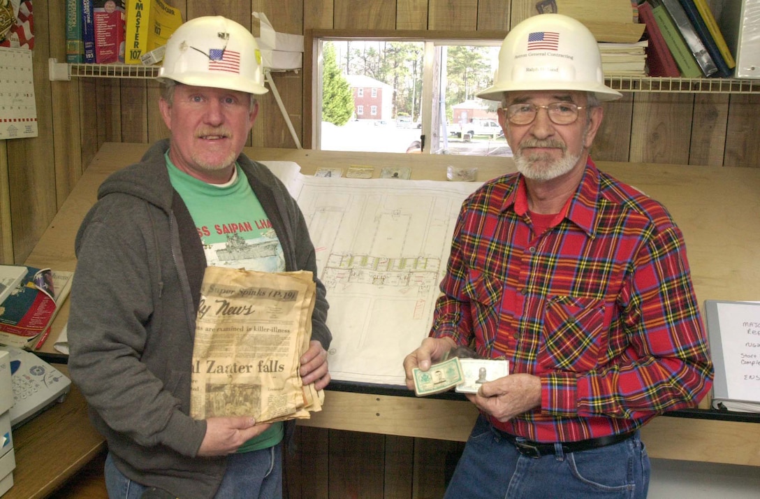 MARINE CORPS BASE CAMP LEJEUNE, N.C.- Retired Master Sgt. Mark Ault and former Marine Ralph Holland display identification cards and newspapers found in the walls of the Stone Bay rifle range shooters barracks. The memoriabilia, along with some live rounds and other keepsakes, are from Marines who trained during the 50s, 60s and 70s. "It was pretty exciting to find this in the walls," said Holland. "We are going to give all this to the museum, but for now it's exciting to wonder what happened to these Marines after they finished their training here." (Official Marine Corps photo by Lance Cpl. Shane Suzuki)