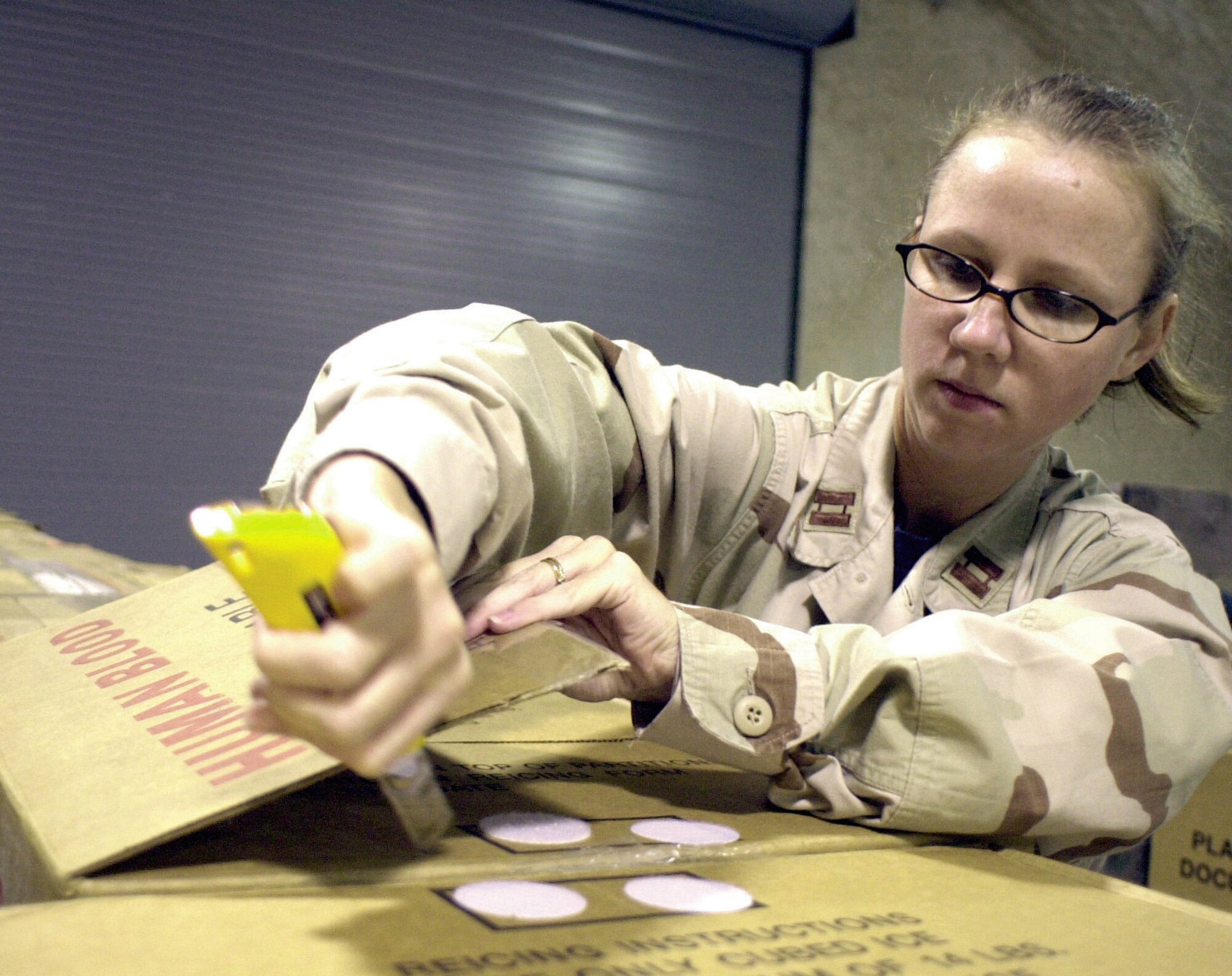 SOUTHWEST ASIA -- Capt. Jessica Fritz cuts open a box of red blood cells from a shipment.  She is the officer in charge of the blood transshipment center at a forward-deployed location here.  (U.S. Air Force photo by Staff Sgt. Bryan Bouchard)