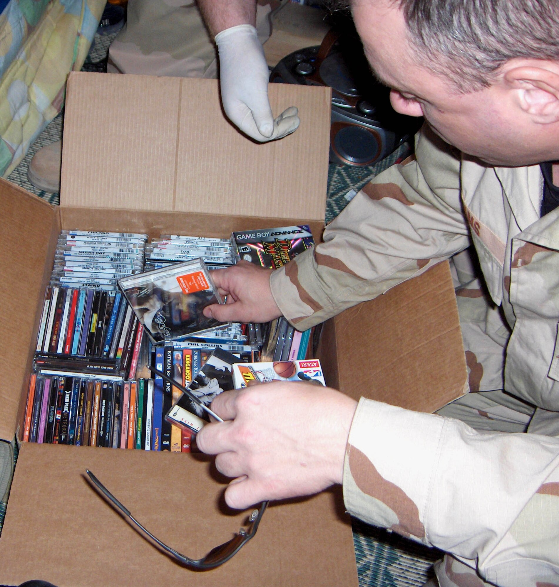 KIRKUK AIR BASE, Iraq -- An Airman here goes through a box of stolen CDs and DVDs that was recovered during a surprise inspection of areas inhabited by third-country workers and American contractors.  The operation successfully broke up an AAFES theft ring.  (U.S. Air Force photo by Maj. Robert Baird)