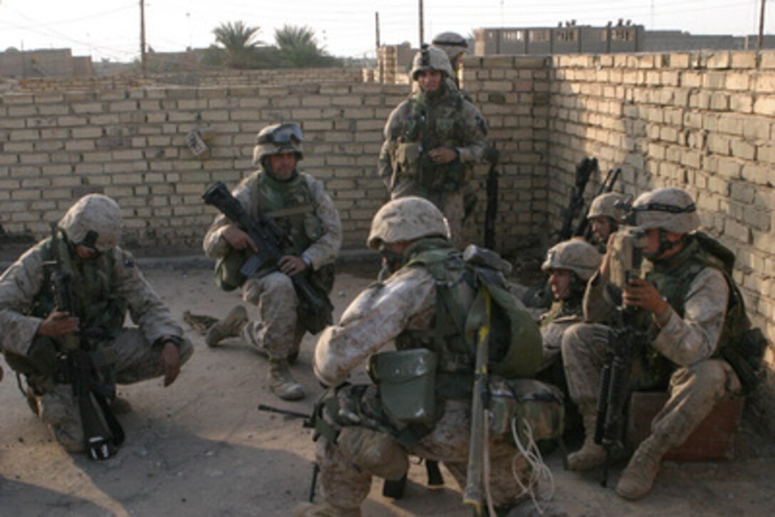 U.S. Marines huddle behind walls as they receive instructions about their next move after a M1A1 tank eliminates the Iraqi insurgents in a house the Marines were receiving fire from in Fallujah, Iraq, in support of Operation al Fajr (New Dawn) on Dec. 10, 2004. Operation al Fajr is an offensive operation to eradicate enemy forces within the city of Fallujah in support of continuing security and stabilization operations in the Al Anbar province of Iraq. The Marines are assigned to 3rd Platoon, I Company, 3rd Battalion, 5th Marine Regiment, 1st Marine Division. 
