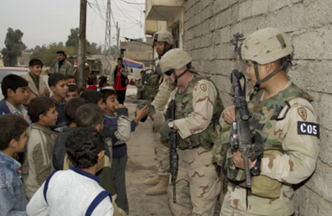 U.S. Army 1st Lt. Jason Stanley (left), Staff Sgt. Chris McCarthy (center) and Capt. Phon Sundra talk with Iraqi children during a patrol in Mosul, Iraq, on Dec. 11, 2004. The soldiers are assigned to Charlie Company, 1st Battalion, 24th Infantry Regiment, 1st Brigade, 25th Infantry Division. 