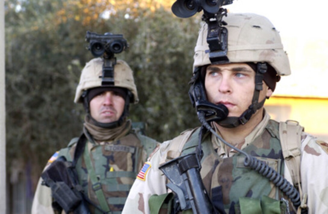 U.S. Army soldiers guard the courtyard of a house during an early morning raid in Al Shahabi, Iraq, on Dec. 17, 2004. The raid by soldiers of Bravo Company, 1st Battalion, 85th Armor, Task Force Tacoma, 2nd Brigade Combat Team resulted in the detention of three high value target individuals. 