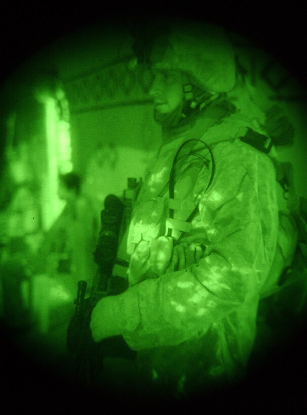 Seen through night vision gear, Lance Cpl. Gary Cremeans, machine gunner, 3rd Platoon, Company B, 1st Battalion, 23rd Marine Regiment, 31st Marine Expeditionary Unit, and a 24-year-old HVAC technician from Austin, Texas, stands guard over two suspected insurgents, secured and detained in the background, during a nightly cordon and knock raid around Ramadi, Iraq, Dec. 23. The raid was part of a larger effort to maintain security and stability by disrupting the insurgency prior to elections. Photo by Cpl. Paul W. Leicht