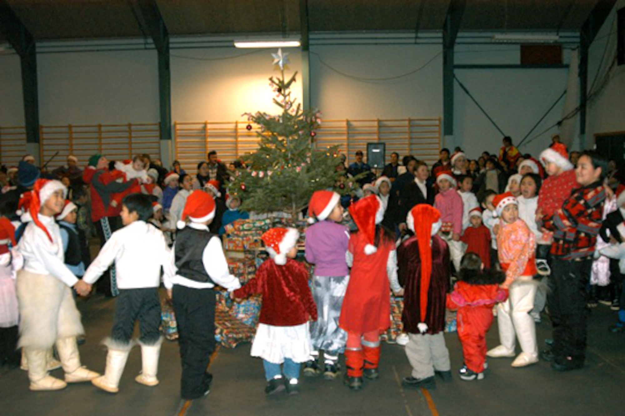 QAANAAQ, Greenland -- Children here dance around the Christmas tree just before opening gifts at the Julemand Celebration on Dec. 20.  The gifts were provided by the Airmen of Thule Air Base.  (U.S. Air Force photo by 1st Lt. Jennifer Tribble)  