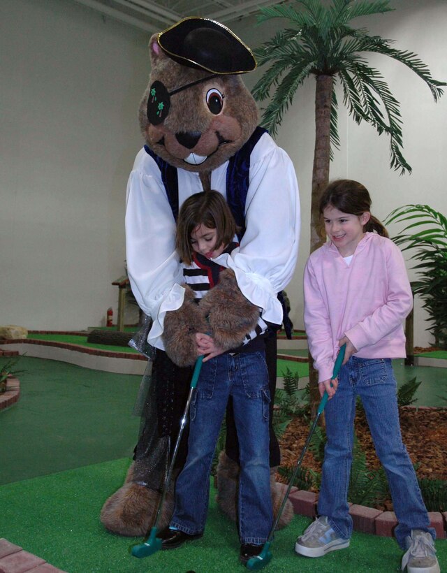 MINOT AIR FORCE BASE, N.D. -- Darby the Dakrat, the 5th Services Squadron mascot, gives Jacqui Santa Ana (left) and Sidney Rogerson putting tips at the opening day of Treasure Island here Dec. 23.  Treasure Island is an indoor recreation center featuring a skating park, miniature golf course, batting cages and rock climbing wall.  (U.S. Air Force photo by Airman 1st Class Danny Monahan)