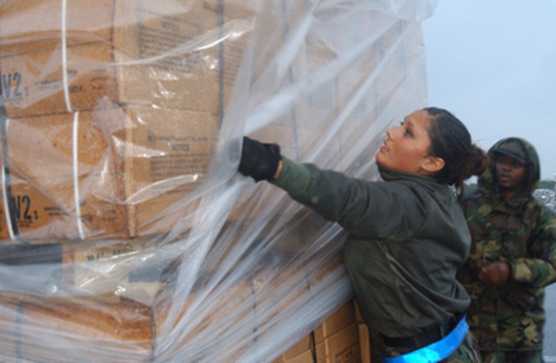 U.S. Air Force Airman Autumn McHam (left) helps cover an aircraft pallet of Meals Ready to Eat at Kadena Air Base, Japan, on Dec. 28, 2004. The meals will be flown to Southeast Asia as part of disaster relief following an earthquake that caused tsunami waves that affected 12 countries. McHam is assigned to the 733rd Air Mobility Squadron, 18th Air Wing. 