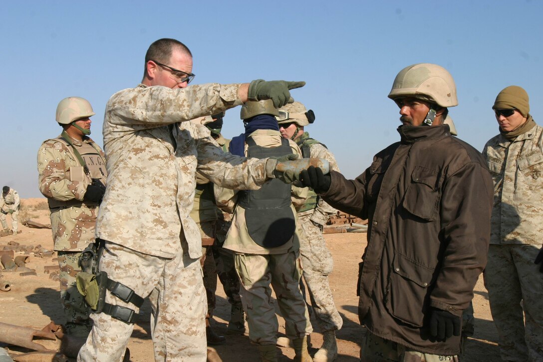 Master Sgt. Michael W. Snow, Explosive Ordnance Disposal chief, Marine Expeditionary Unit Service Support Group 11, 11th MEU (Special Operations Capable), directs an Iraqi National Guard soldier where to put a mortar containing explosive residue during an unexploded ordnance cleanup operation near a 1,200 year-old medieval Persian fort, Dec. 29.