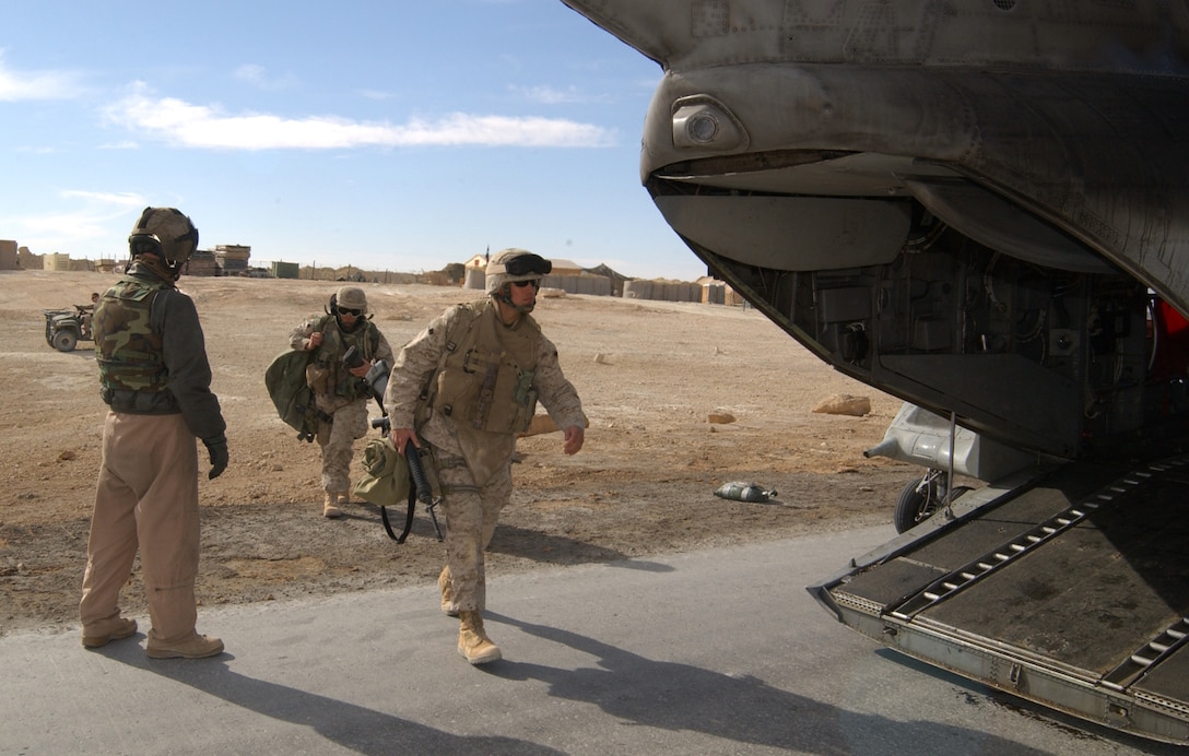 Master Sgt. Daniel S. Nickle, CH-46E Sea Knight crew chief, Marine Medium Helicopter Squadron 365, Marine Aircraft Group 16, 3rd Marine Aircraft Wing, guides a group of passengers onto his helicopter at a forward operating base near the Syrian border with Iraq Dec. 30. Troop and cargo transport is a recurring mission the squadron performs for the I Marine Expeditionary Force in Iraq that allows the Marines to constantly move their forces about the area quickly.