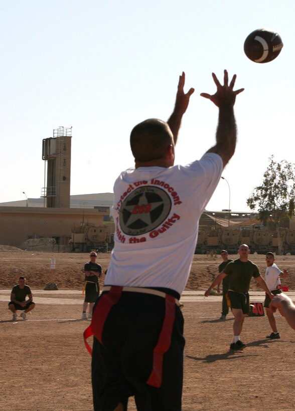Players look on as a Marine receives a pass from his “Gunrunners” teammate during a flag football tournament aboard Al Asad Air Base, Iraq, Dec. 13, 2009. Both service members and civilians come out every month for the tournament, which is organized by the staff at the Hero’s Hall gym and service members.