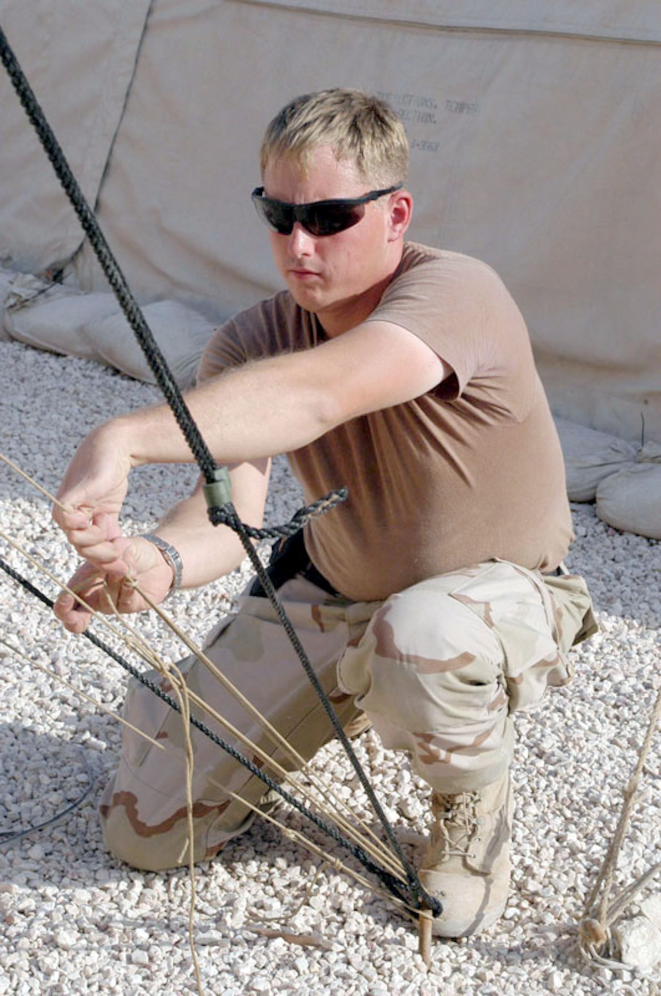 SOUTHWEST ASIA -- Senior Airman Christopher Holmes tightens a support rope on a replacement tent cover at a forward-deployed location.  Airman Holmes is a structural specialist with the 379th Expeditionary Civil Engineer Squadron.  (U.S. Air Force photo by Senior Airman Lynne Neveu)