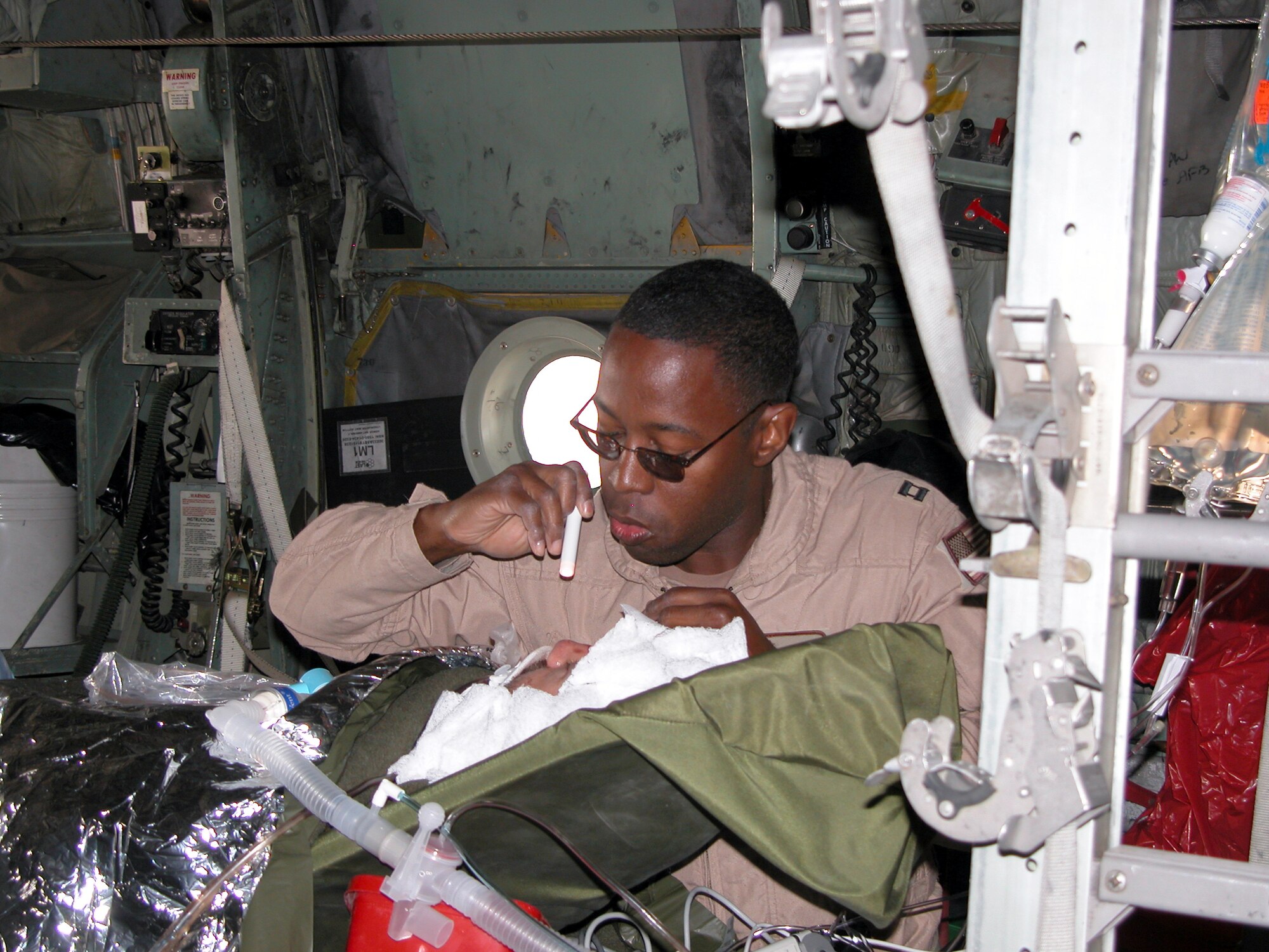 SOUTHWEST ASIA -- Capt. Lionel Lyde checks on a patient during a medical evacuation flight to Baghdad aboard a C-130 Hercules on Jan. 28.  Captain Lyde is a critical care air transport nurse with the 379th Aeromedical Squadron.  (U.S. Air Force photo by Tech. Sgt. Bob Oldham)