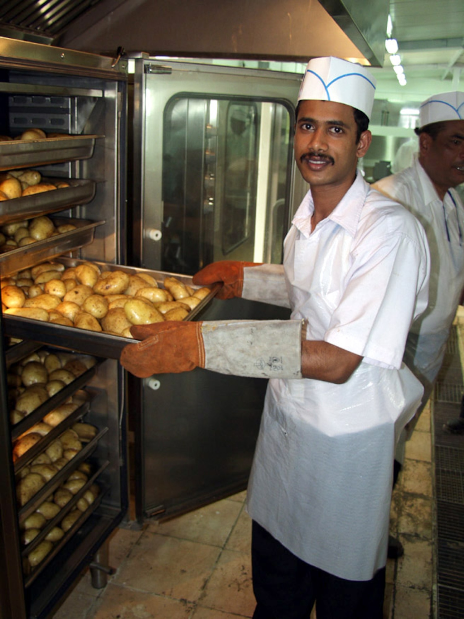 KIRKUK AIR BASE, Iraq -- Pagitra Mondal, a head cook, takes potatoes out of an oven during lunch at the new dining facility here.  The new facility can handle 1,500 people at a time and is able to serve up to 18,000 meals a day.  (U.S. Air Force photo by Tech. Sgt. Jeffrey Williams)