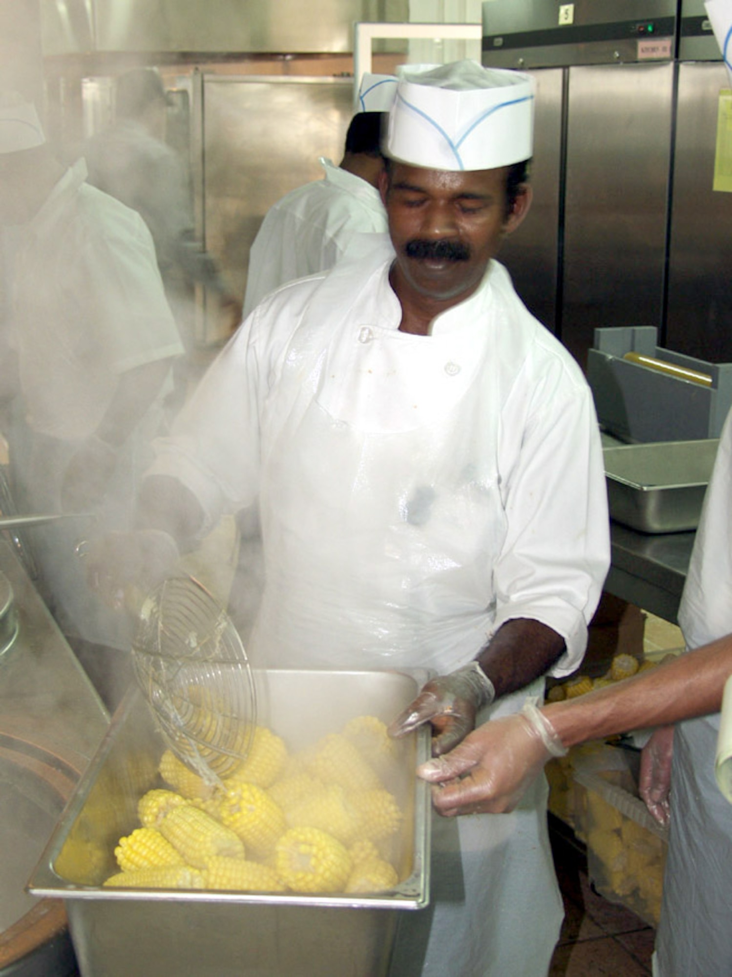 KIRKUK AIR BASE, Iraq -- George Johnson, a head cook, places corn on the cob into a serving basin during a meal at the new dining facility here.  The new facility can handle 1,500 people at a time and is able to serve up to 18,000 meals a day.  (U.S. Air Force photo by Tech. Sgt. Jeffrey Williams)