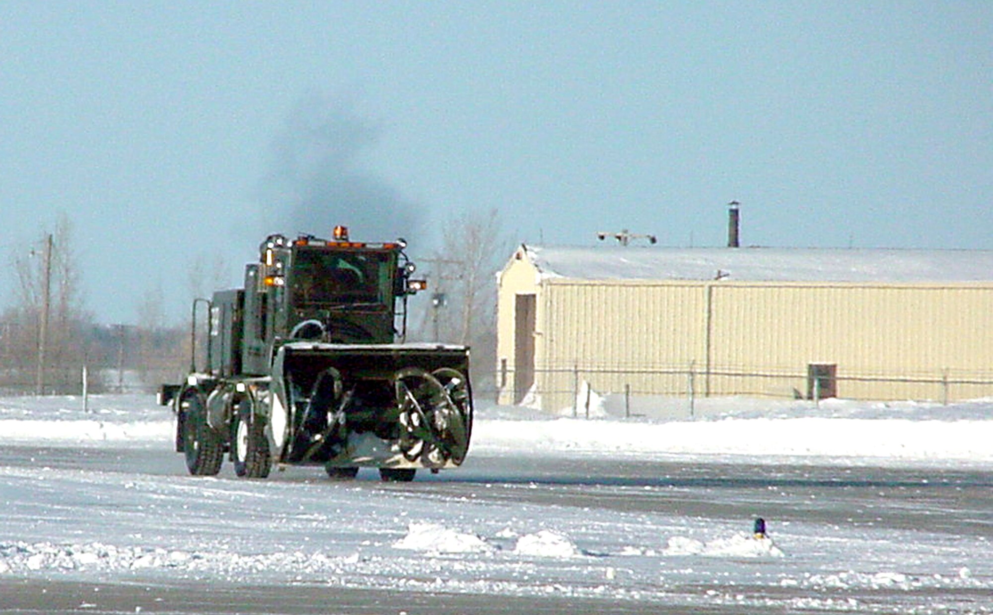 GRAND FORKS AIR FORCE BASE, N.D. -- A snow-removal truck from the 319th Civil Engineer Squadron here moves along an area near the flightline Feb. 3 after blowing some snow off of the ramp.  Less than a week ago the base here received nearly 2 feet of snow and CES crews are still removing snow in many areas.  (U.S. Air Force photo by Staff Sgt. Scott T. Sturkol)