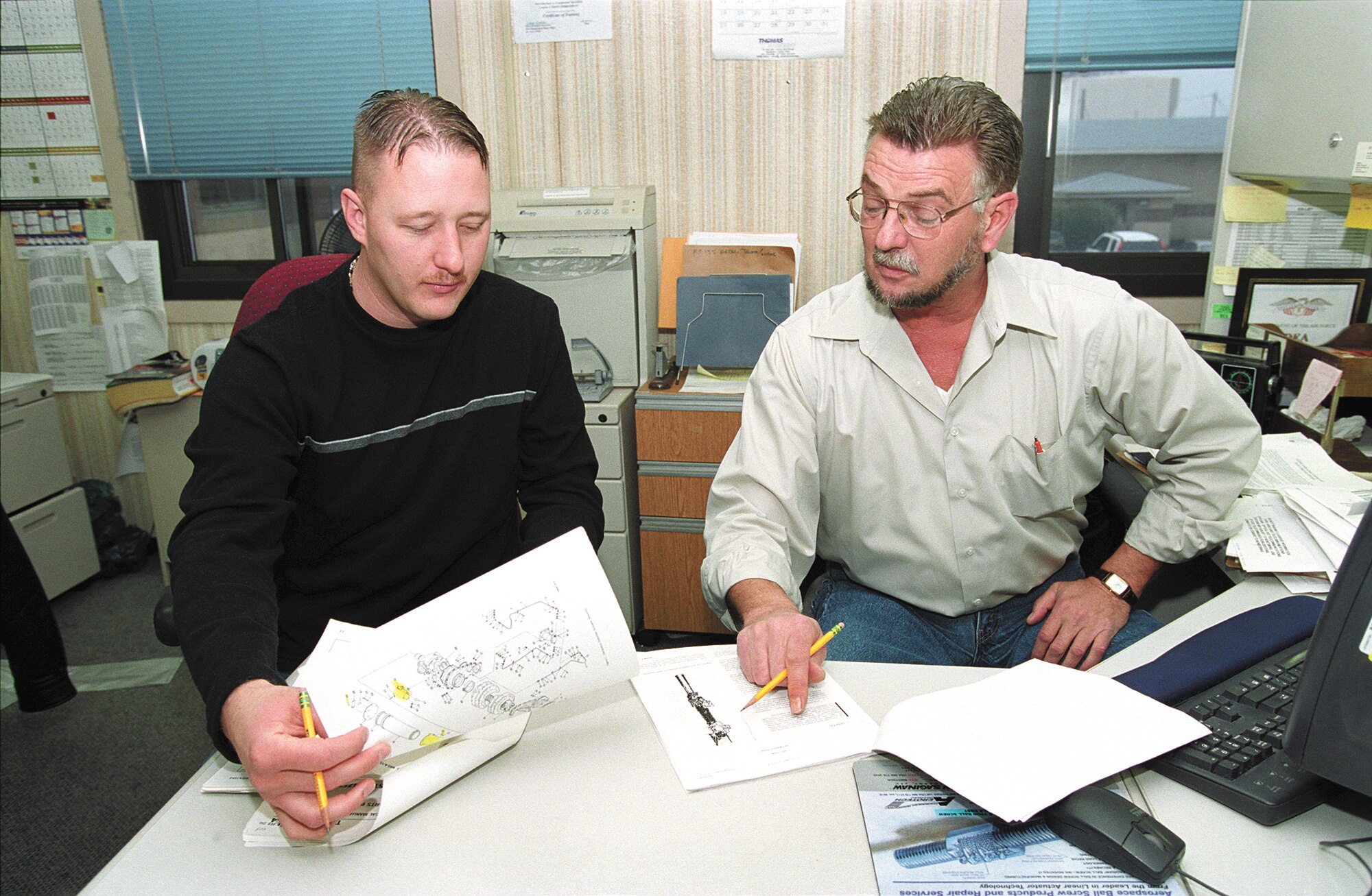 TINKER AIR FORCE BASE, Okla. -- Michael Simmons (left) and Calvin Haugen earned $10,000 under the Innovative Development through Employee Awareness program.  The two men recommended the Air Force not digitize technical orders for the C-141 Starlifter, an aircraft system headed toward retirement.  The suggestion saved the Air Force an estimated $141,340.  Both men are assigned to the logistics directorate's accessories division here.  (U.S. Air Force photo by Margo Wright)