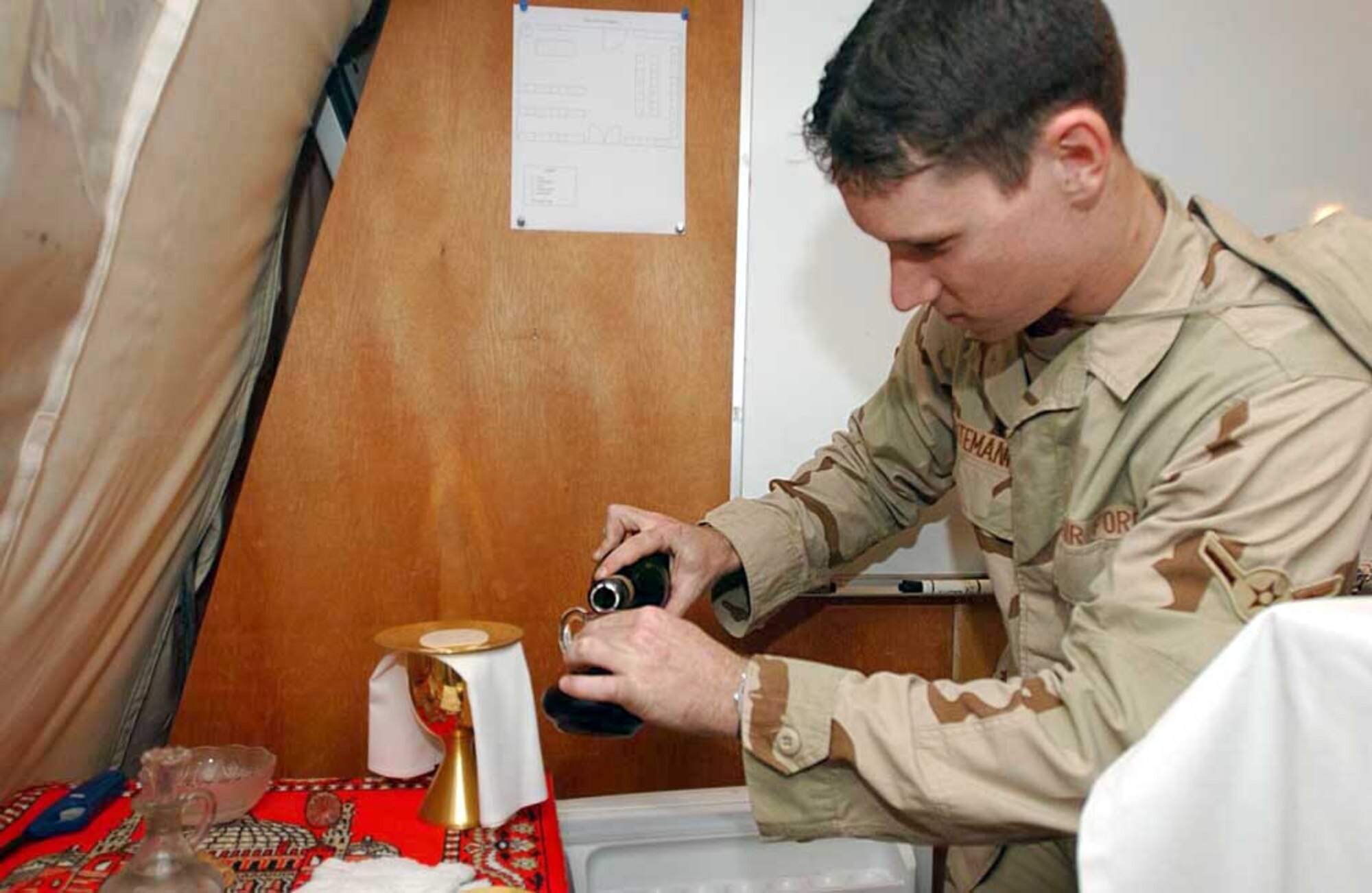 SOUTHWEST ASIA -- Airman Kevin Intemann, a chaplain assistant, prepares for a communion service. Chaplain assistants take care of office functions and the logistical needs of the chapel, so chaplains can concentrate on people in a deployed environment.  Airman Intemann is assigned to the 379th Air Expeditionary Wing.  (U.S. Air Force photo by Senior Airman Lakisha Croley)