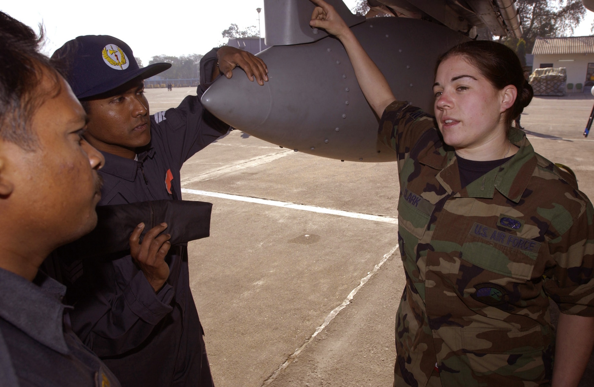 GWALIOR AIR FORCE STATION, India (AFPN) - Senior Airman Colleen Clark (right) discusses emergency fuel shutdown procedures and other F-15 Eagle maintenance issues with Indian air force maintenance workers here.  Airman Clark is a repair and reclamation specialist with the 3rd Equipment Maintenance Squadron deployed here from Elmendorf Air Force Base, Alaska, for Cope India 04.  (U.S. Air Force photo by Tech Sgt. Keith Brown)

