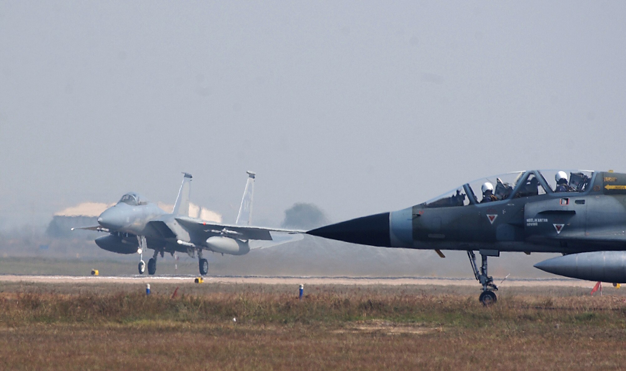 GWALIOR AIR FORCE STATION, India (AFPN) -- As an Indian air force M-2000 Mirage waits to taxi to the runway, a U.S. Air Force F-15 Eagle takes off.  Both American and Indian air forces are participating in Cope India 04, a bilateral dissimilar air combat exercise.  (U.S. Air Force photo by Tech. Sgt. Keith Brown)