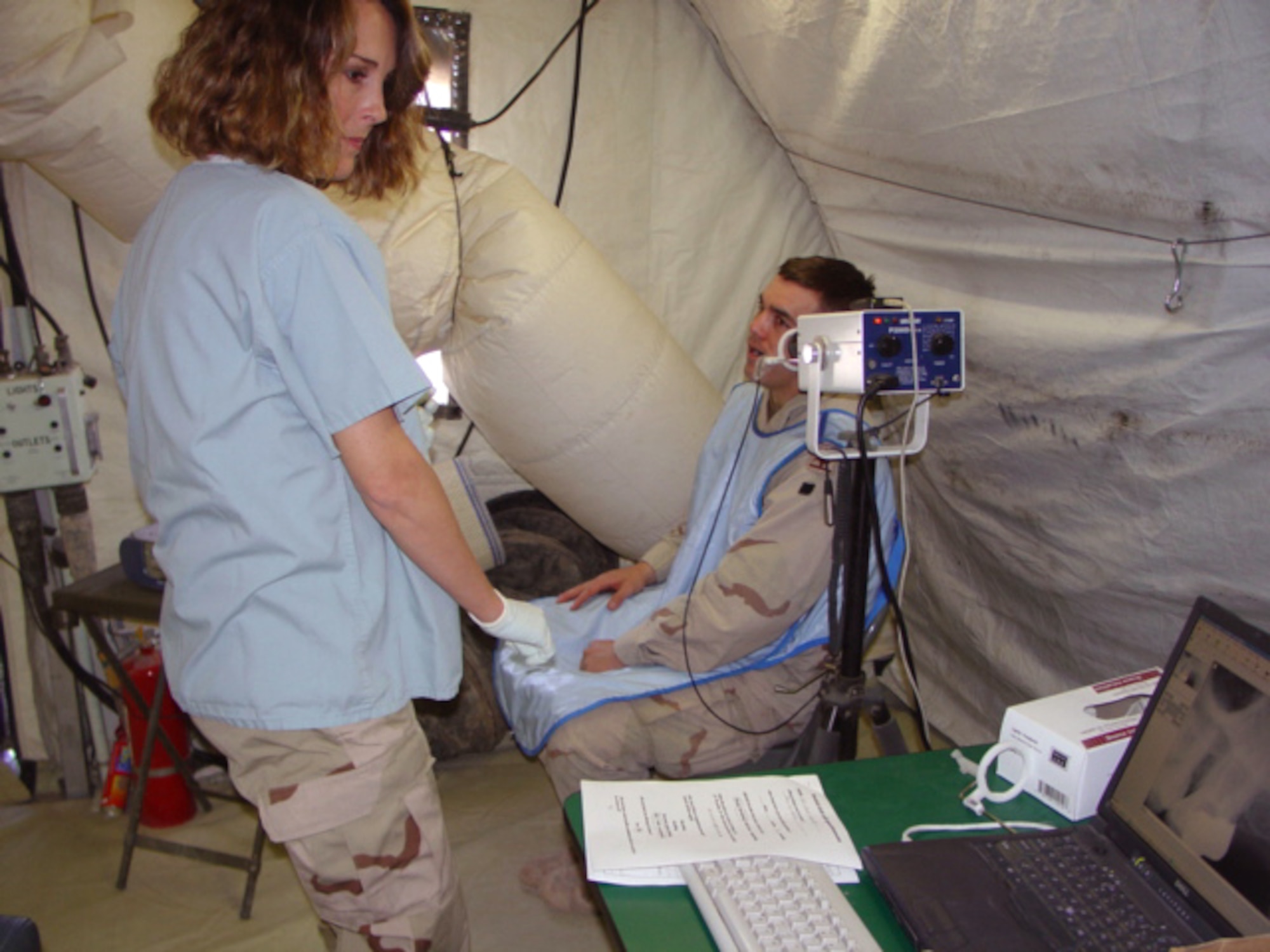 TALLIL AIR BASE, Iraq (AFPN) -- Staff Sgt. Candy Ables (left) uses hi-tech digital X-ray equipment to create an image of Army Sgt. Chad Hyatt's teeth on a laptop computer.  Sergeant Ables is a dental technician deployed here from Lackland Air Force Base, Texas.  (U.S. Air Force photo by Capt. Mo Schumann)