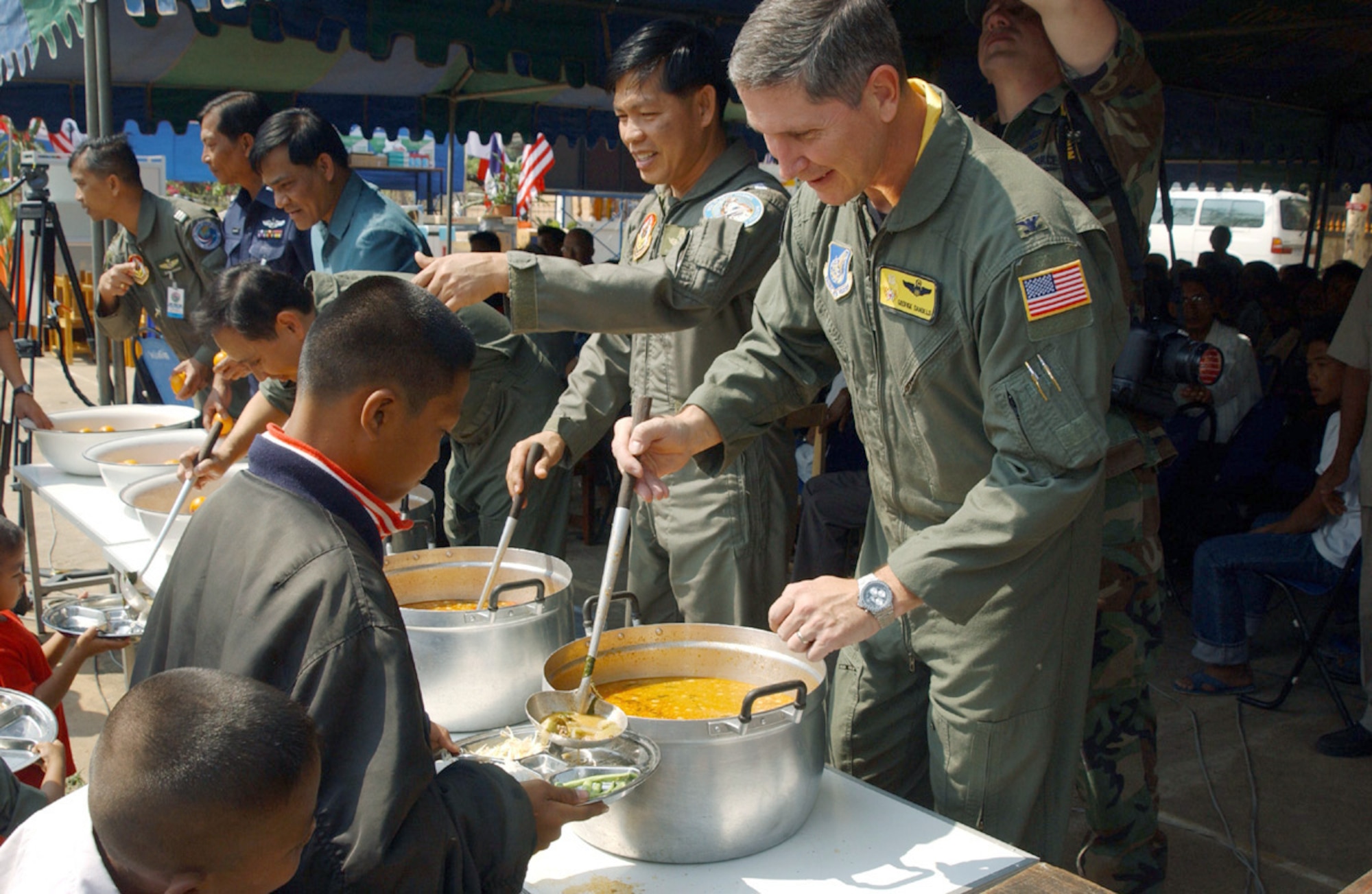 KORAT, Thailand -- Col. George Daniels (right) and Group Capt. Songtam Chokanapitak serve lunch to a group of children during a visit to a local Thai school.  Participants from exercise Cope Tiger '04 delivered much-needed supplies to the school.  Colonel Daniels is the U.S. Air Force exercise director and Captain Chokanapitak is an airman with the Royal Thai air force.  (U.S. Air Force photo by Tech. Sgt. Jonathan Doti)