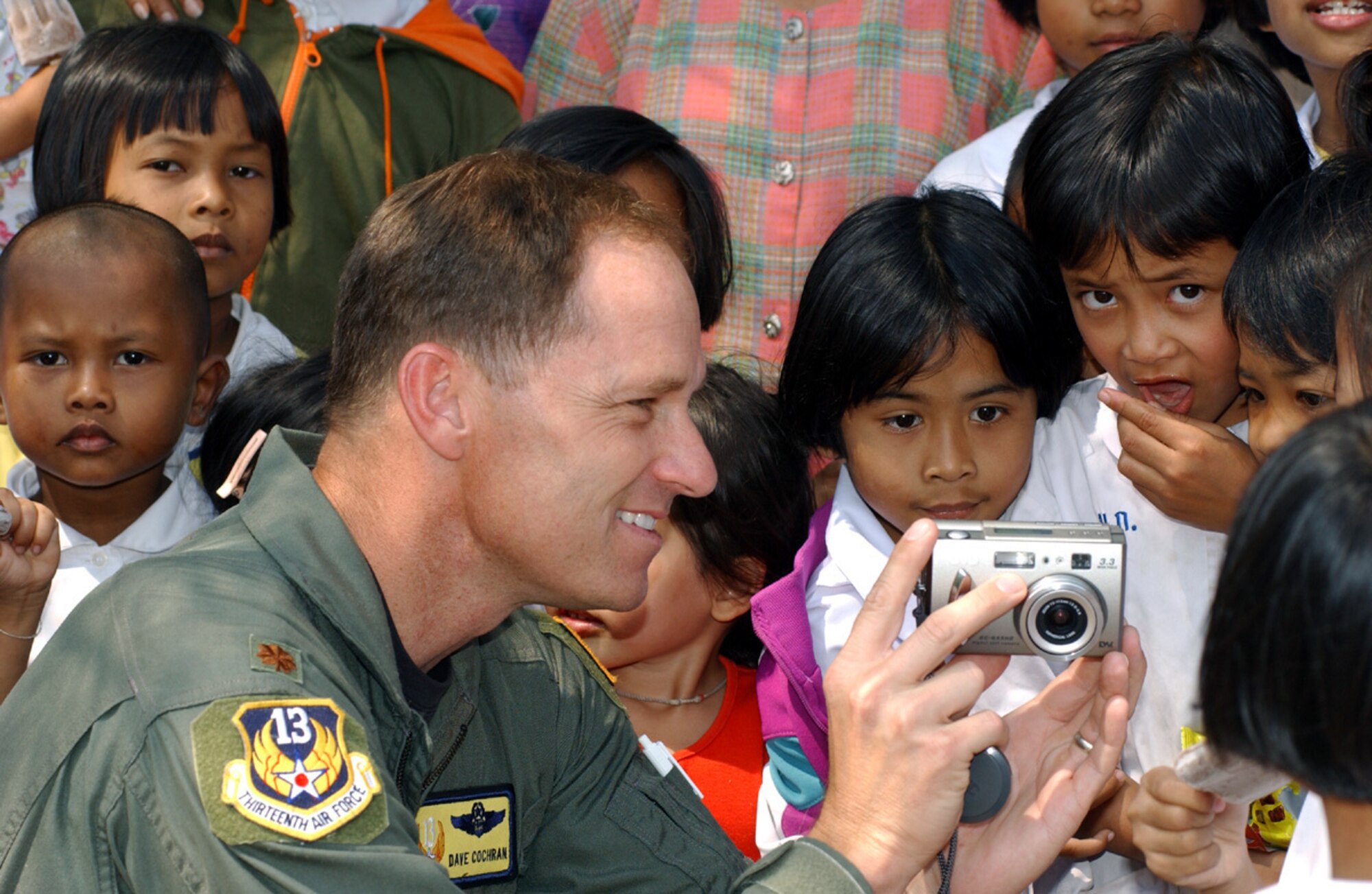 KORAT, Thailand -- Maj. Dave Cochran shows a digital camera to a group of curious school children Feb. 16 during a visit to a local Thai school.  Participants from exercise Cope Tiger '04 delivered much-needed supplies to the school.  Major Cochran is deployed here from Andersen Air Force Base, Guam.  (U.S. Air Force photo by Tech. Sgt. Jonathan Doti)