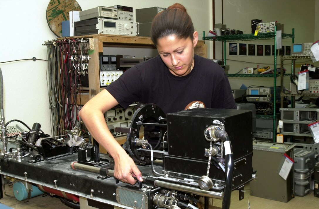 SOUTHWEST ASIA -- Staff Sgt. Andrea Lopez prepares to turn a digital test set on its side so she can inspect its circuit cards.  The test set, which checks out guidance systems on missiles, was brought to the precision measurement equipment laboratory because of power-up and self-test failures.  Sergeant Lopez is a PMEL technician with the 379th Expeditionary Maintenance Squadron and is deployed from Aviano Air Base, Italy.  (U.S. Air Force photo by Senior Airman Chawntain Young)