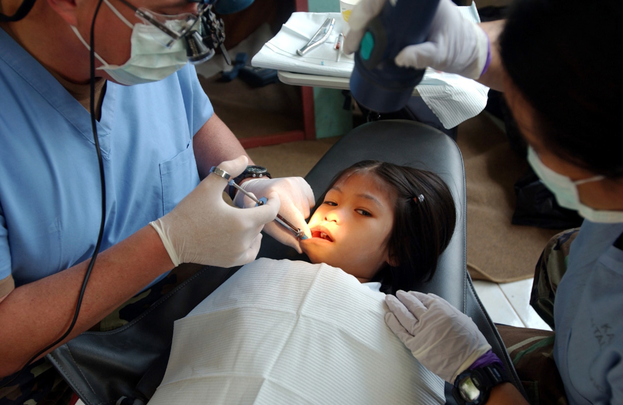 KORAT, Thailand -- Lt. Col. Steven Hyslop (left) prepares to extract a tooth from a Thai girl.  A team of 20 U.S. physicians, dentists and medical technicians, here to conduct a medical and dental civic outreach program during Cope Tiger '04, treated more than 2,100 people during the three-day event.  Colonel Hyslop is deployed here from Kadena Air Base, Japan.  (U.S. Air Force photo by Tech. Sgt. Jonathan Doti)