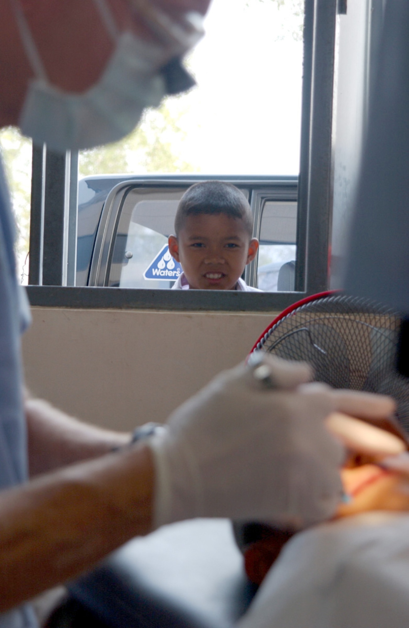KORAT, Thailand -- A curious boy looks on as an Air Force dentist performs an exam on a Thai villager.  A team of 20 U.S. physicians, dentists and medical technicians, here to conduct a medical and dental civic outreach program during Cope Tiger '04, treated more than 2,100 people during the three-day event.  (U.S. Air Force photo by Tech. Sgt. Jonathan Doti)