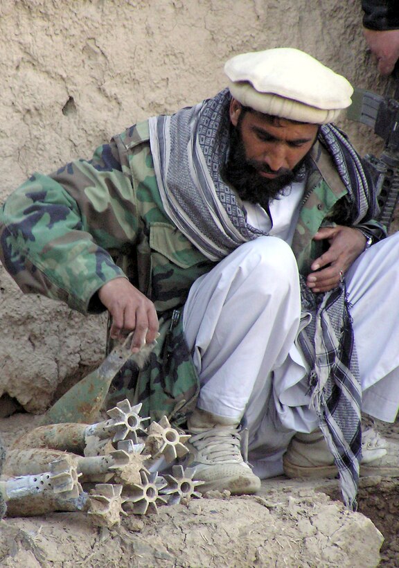 QALAKHEL, Afghanistan -- A village member helps unearth dozens of old, live mortar rounds embedded in a mud wall. Hundreds of weapons were found by agents of the Air Force Office of Special Investigations' anti-terrorism specialty team deployed from Lackland Air Force Base, Texas.  (U.S. Air Force photo by Tech Sgt. Brian Davidson)