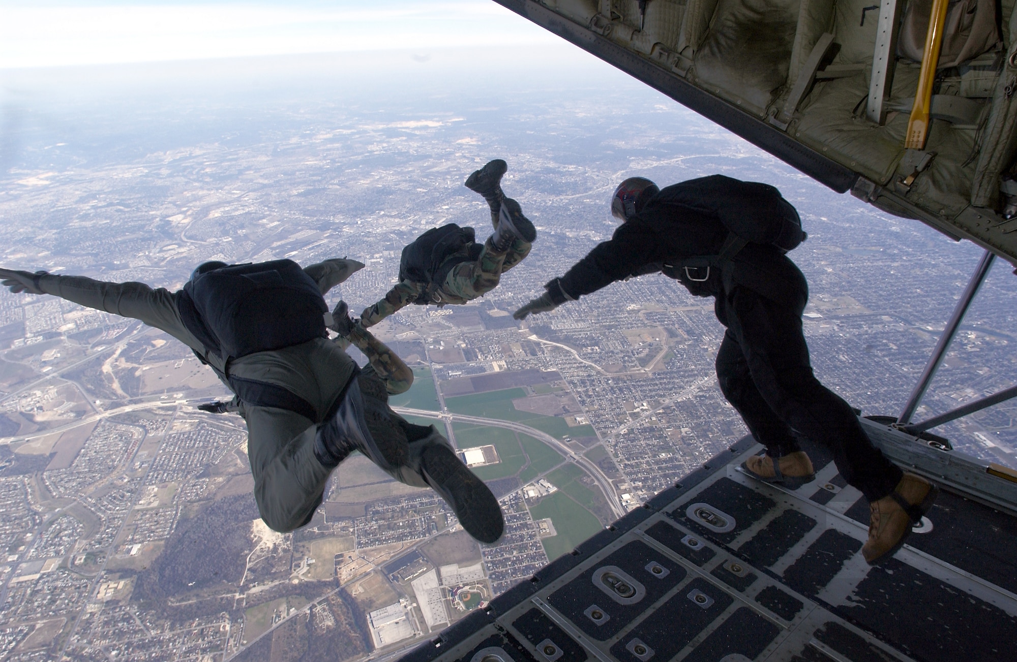 OVER LACKLAND AIR FORCE BASE, Texas -- Airmen from the 346th and 342nd Training Squadrons perform a high-altitude, low-opening parachute jump onto the base's parade grounds below Feb. 21.  The proficiency training exercise had combat controllers and pararescuemen exiting the aircraft at 9,500 feet, traveling at 130 knots, and landing on a precise target at the drop zone.  (U.S. Air Force photo by Master Sgt. Lance S. Cheung)