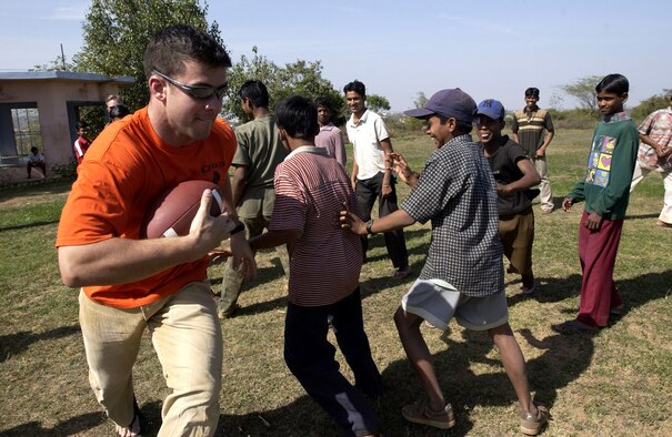 GWALIOR, India -- Capt. Jeffery Mohr teaches an Indian boy how to play football at a local orphanage during a recent trip to donate toys and supplies to the children.  About 130 airmen from Elmendorf Air Force Base, Alaska, are here for Cope India '04, a bilateral exercise with the Indian air force.  Captain Mohr is an F-15 Eagle pilot with the 19th Fighter Squadron at Elmendorf.  (U.S. Air Force photo by Tech. Sgt. Keith Brown)