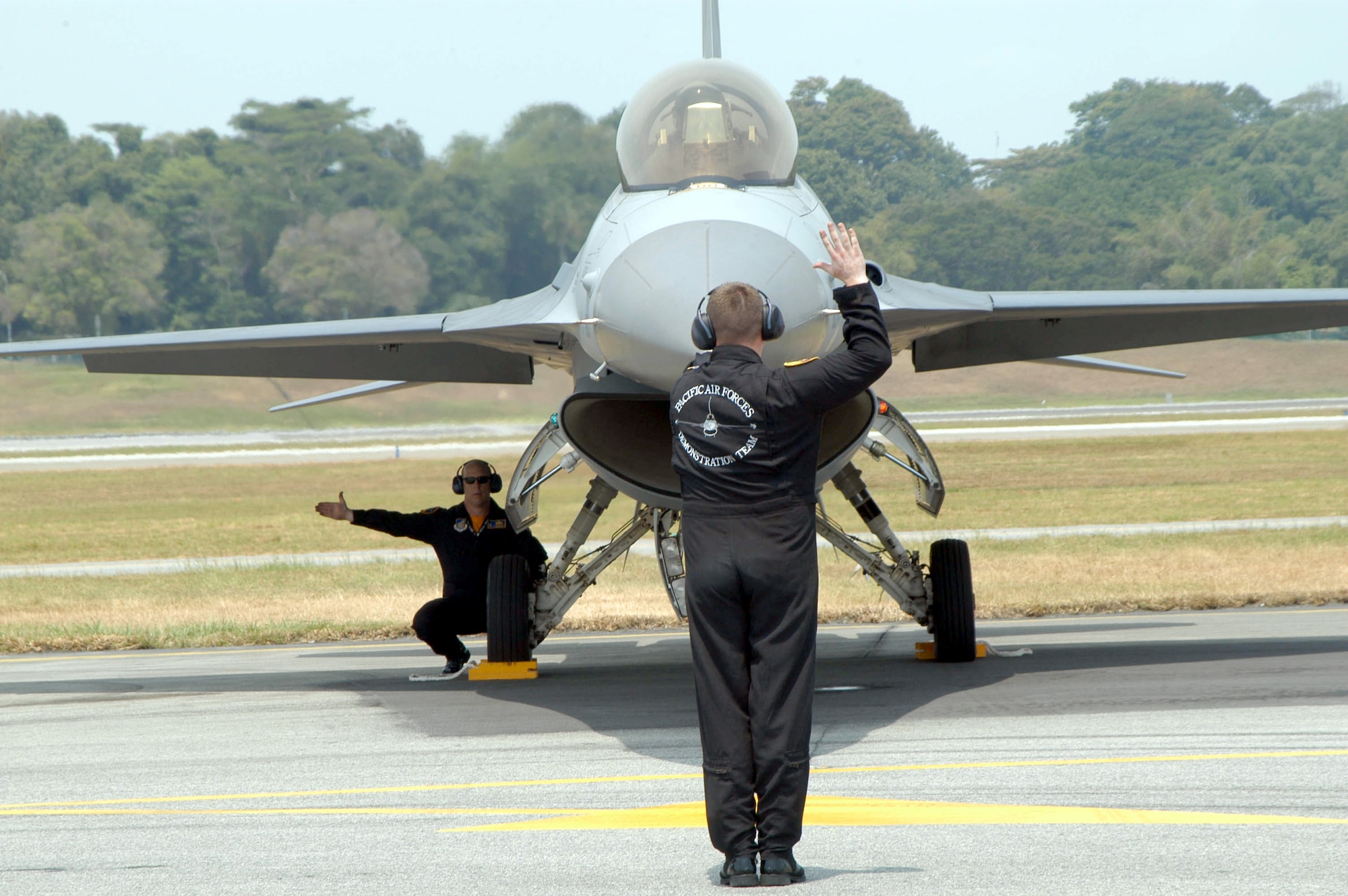 SINGAPORE -- Staff Sgt. Matt Winters and Tech. Sgt. Tim Burnett check an F-16 Fighting Falcon with the pilot, Capt. Keith Rockow, before takeoff.  The airmen are all part of the Pacific Air Forces F-16 demonstration team from the 14th Fighter Squadron at Misawa Air Base, Japan.  They are here supporting Asian Aerospace 2004.  (U.S. Navy photo by Lt. Chuck Bell)