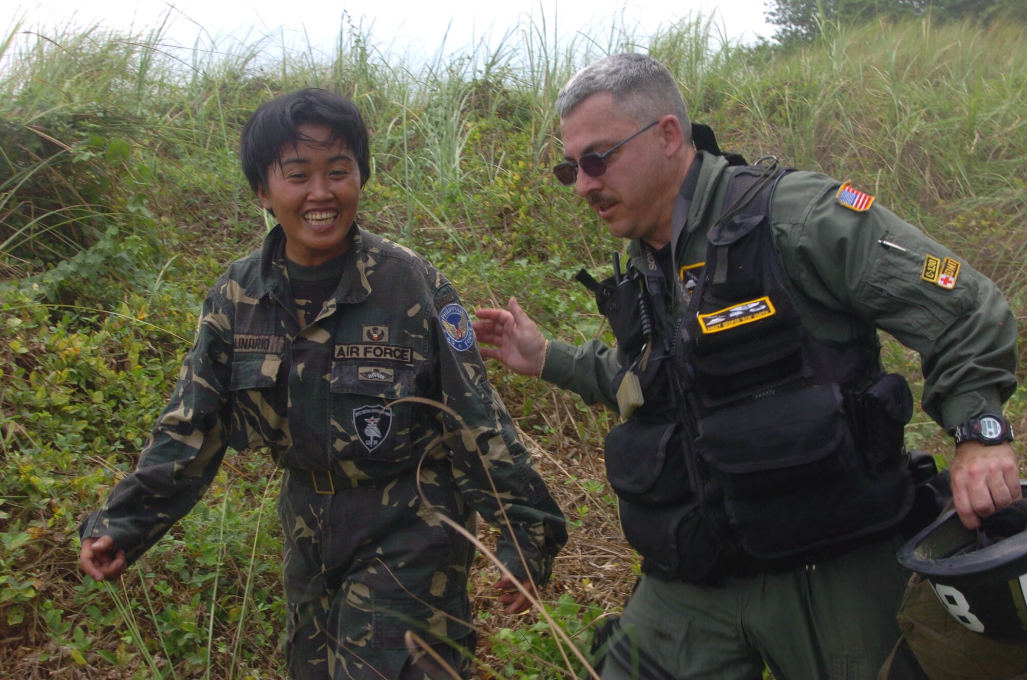 BASA AIR BASE, Philippines -- Master Sgt. George Smith walks with Airwoman Cherry Ann Apolinario of the Philippine air force after she jumped from a C-130 Hercules on Feb. 25 during exercise Balikatan 2004 here.  Sergeant Smith is a medical technician from the 36th Airlift Squadron at Yokota Air Base, Japan.  Balikatan is an annual bilateral exercise that demonstrates U.S. resolve and commitment to train, advise and assist the Philippine government.  (U.S. Air Force photo by Master Sgt. Val Gempis)
