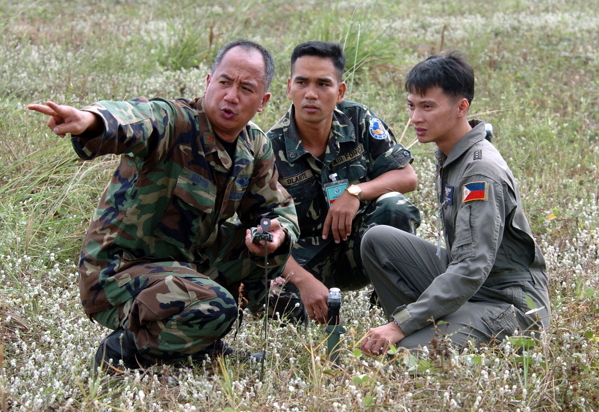 BASA AIR BASE, Philippines -- Maj. Manny Martin (left) uses a compass to explain proper cargo airdrop procedures to Philippine air force Capt. Erich Nazario (right) and Sgt. Victorio Olarte at a drop zone here Feb. 25 during exercise Balikatan 2004.  Major Martin is an air mobility liaison officer from the 25th Air Support Operations Squadron at Hickam Air Force Base, Hawaii.  Balikatan is an annual bilateral exercise that demonstrates U.S. resolve and commitment to train, advise and assist the Philippine government.  (U.S. Air Force photo by Master Sgt. Val Gempis)