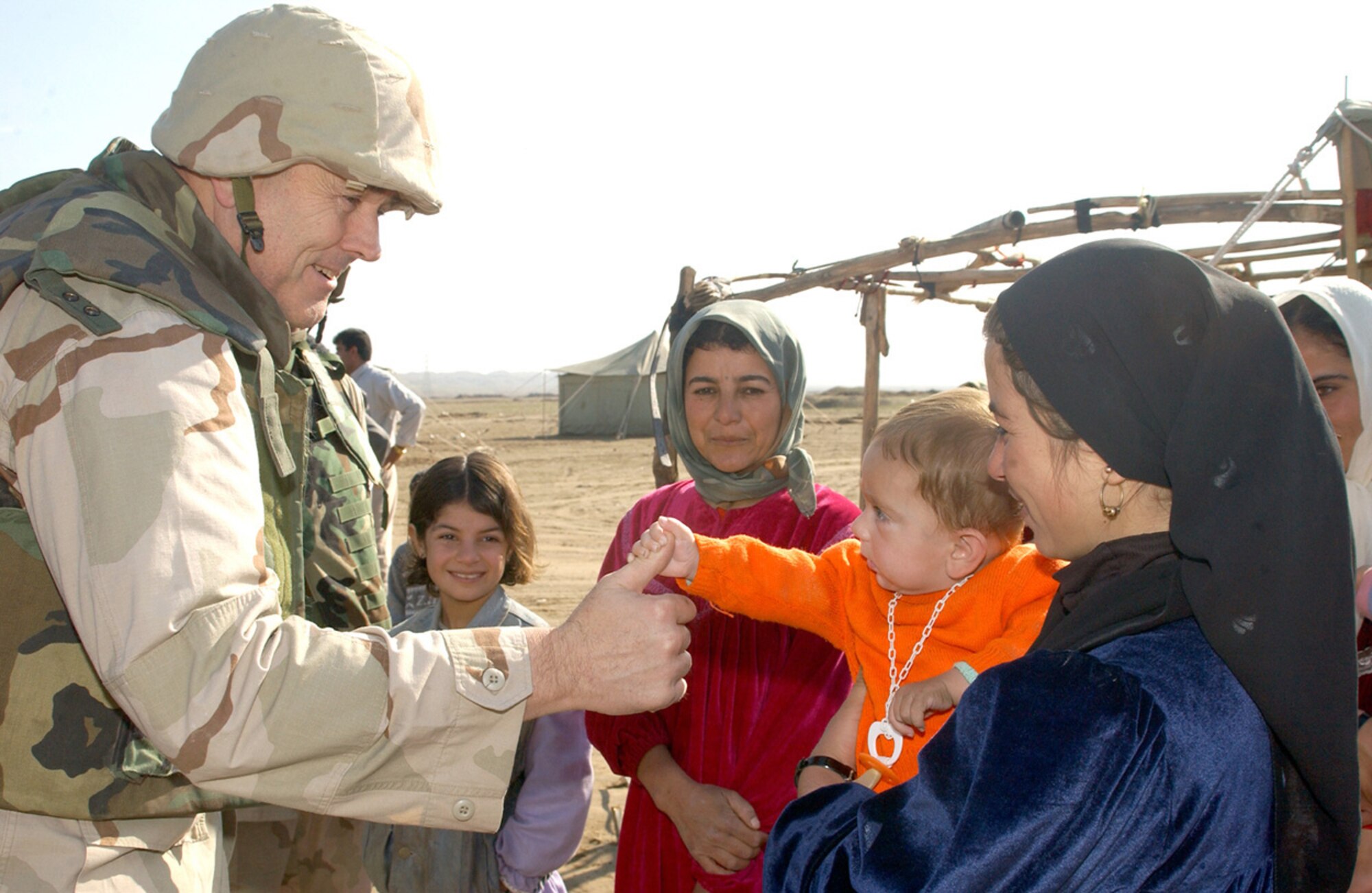 KIRKUK, Iraq -- Chaplain (Lt. Col.) Gary Garvey's thumb is held by a curious infant during a visit to a local village.  Airmen and soldiers delivered several loads of donated boxed goods sent from the United States.  Chaplain Garvey is assigned to the 506th Air Expeditionary Group.  (U.S. Air Force photo by Airman 1st Class Alicia Sarkkinen)