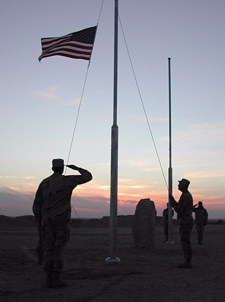 SOUTHWEST ASIA -- Senior Master Sgt. Barry Luttrell (foreground) salutes as Chief Master Sgt. Vance Clarke lowers the American flag at an undisclosed location. Sergeant Luttrell and Chief Clarke are assigned to the 386th Air Expeditionary Wing. (U.S. Air Force photo by Senior Airman James C. Dillard)