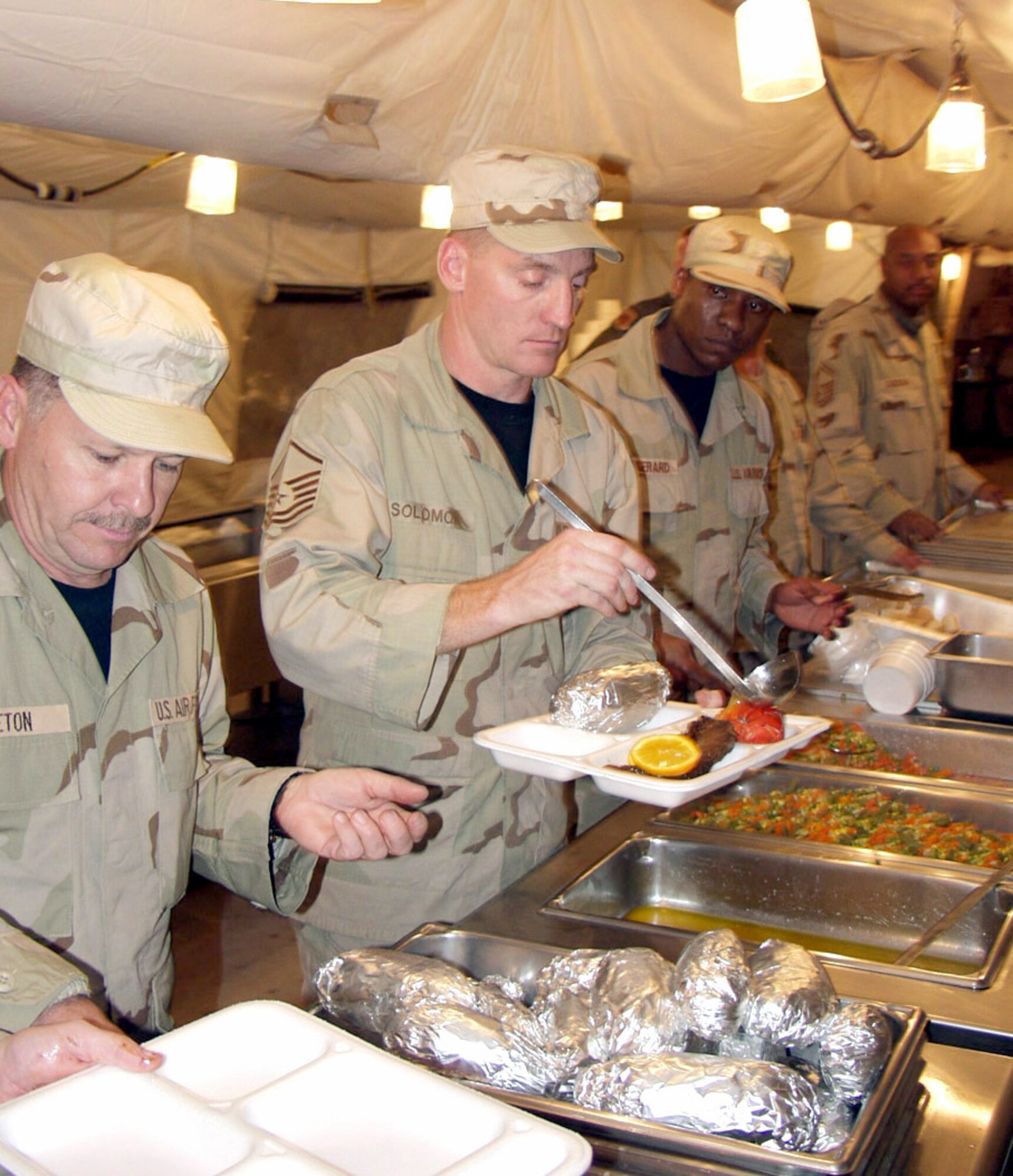 KIRKUK AIR BASE, Iraq -- Master Sgt. Jim Solomon serves up a plate of steak and lobster during the December birthday meal here.  Sergeant Solomon is assigned to the 506th Expeditionary Services Squadron.  (U.S. Air Force photo by Tech. Sgt. Jeffrey Williams)