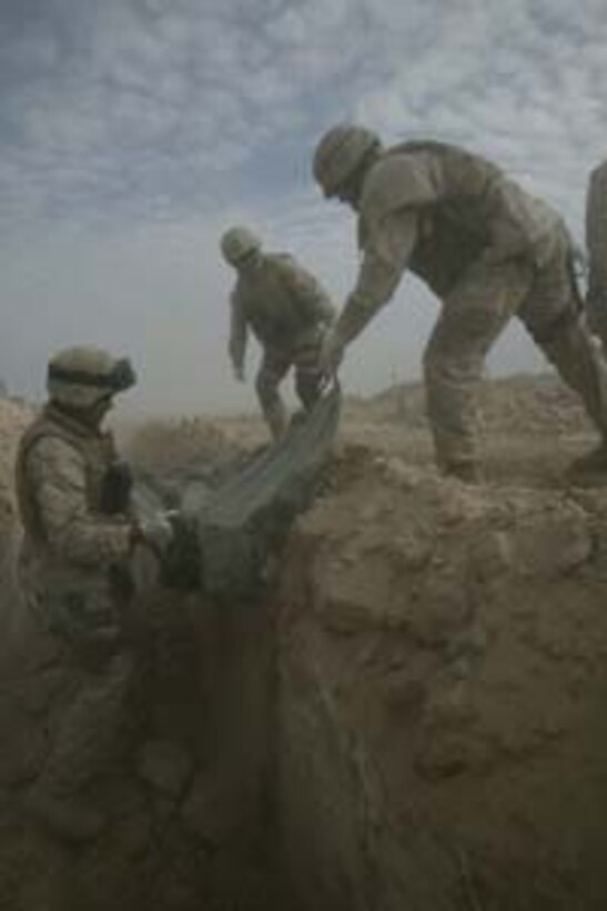Marines with the Provisional Mortuary Affairs Company, which included a detachment of Marines from Bravo Company, 2nd Transportation Support Battalion, use stretchers to carry the bodies of enemy insurgents from trucks to their gravesite Dec. 11, 2004, on the northern edge of Fallujah. In addition to convoying thousands of tons of supplies to U.S. military forces throughout western Iraq, Bravo Co. was also tasked with a variety of other jobs during their deployment, to include the collection and burial of more than 460 enemy killed in action during Operation Al Fajr. The Camp Lejeune, N.C.-based unit is returning to the United States this month after more than seven months of duty in Iraq with the 1st Force Service Support Group.